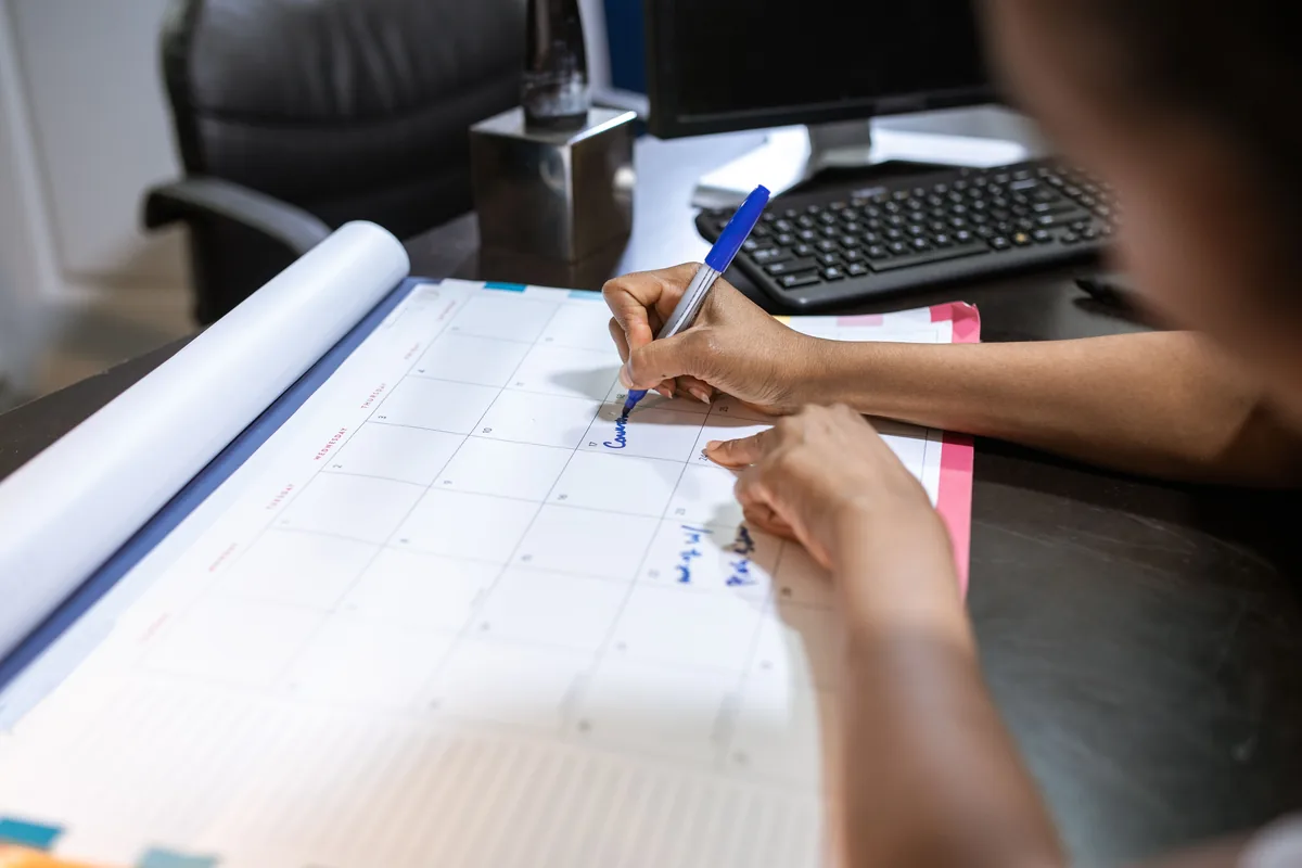 Air Concierge management fees, Hands writing on a large sheet of paper beside a keyboard on a desk