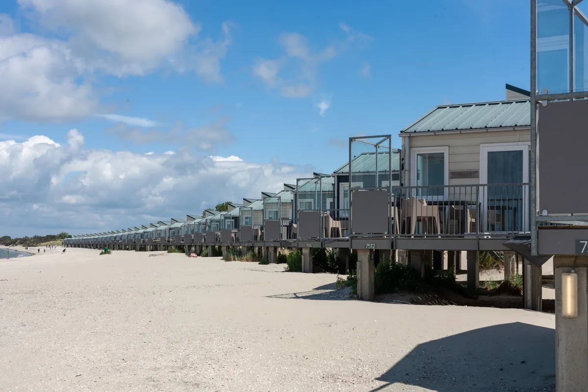 best Airbnb management company alternatives, Long row of stilt houses lining a sandy beach