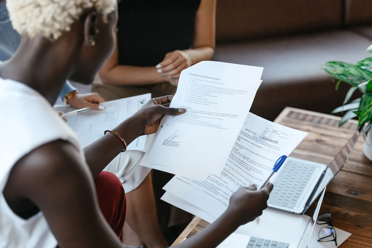 vacation rental management company fees, Two people comparing printed documents across a table
