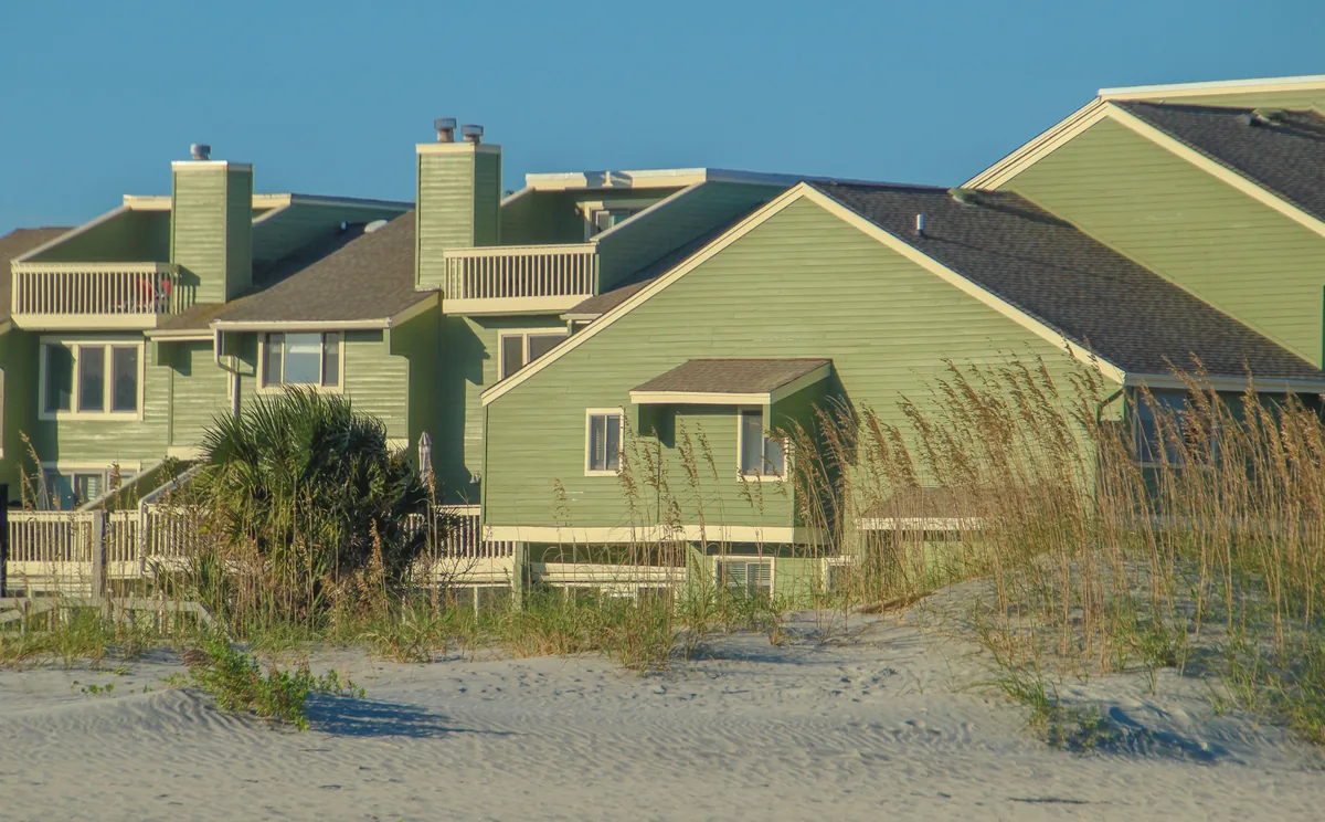 Awning alternatives for Airbnb owners, Green-clad beach houses behind sea oats on a dune