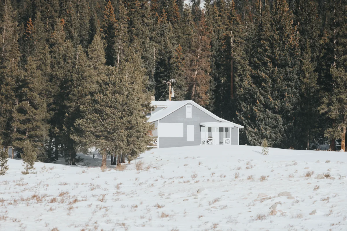 Effortless Rental Group management fees, White house standing alone in a snow-covered meadow at the edge of a pine