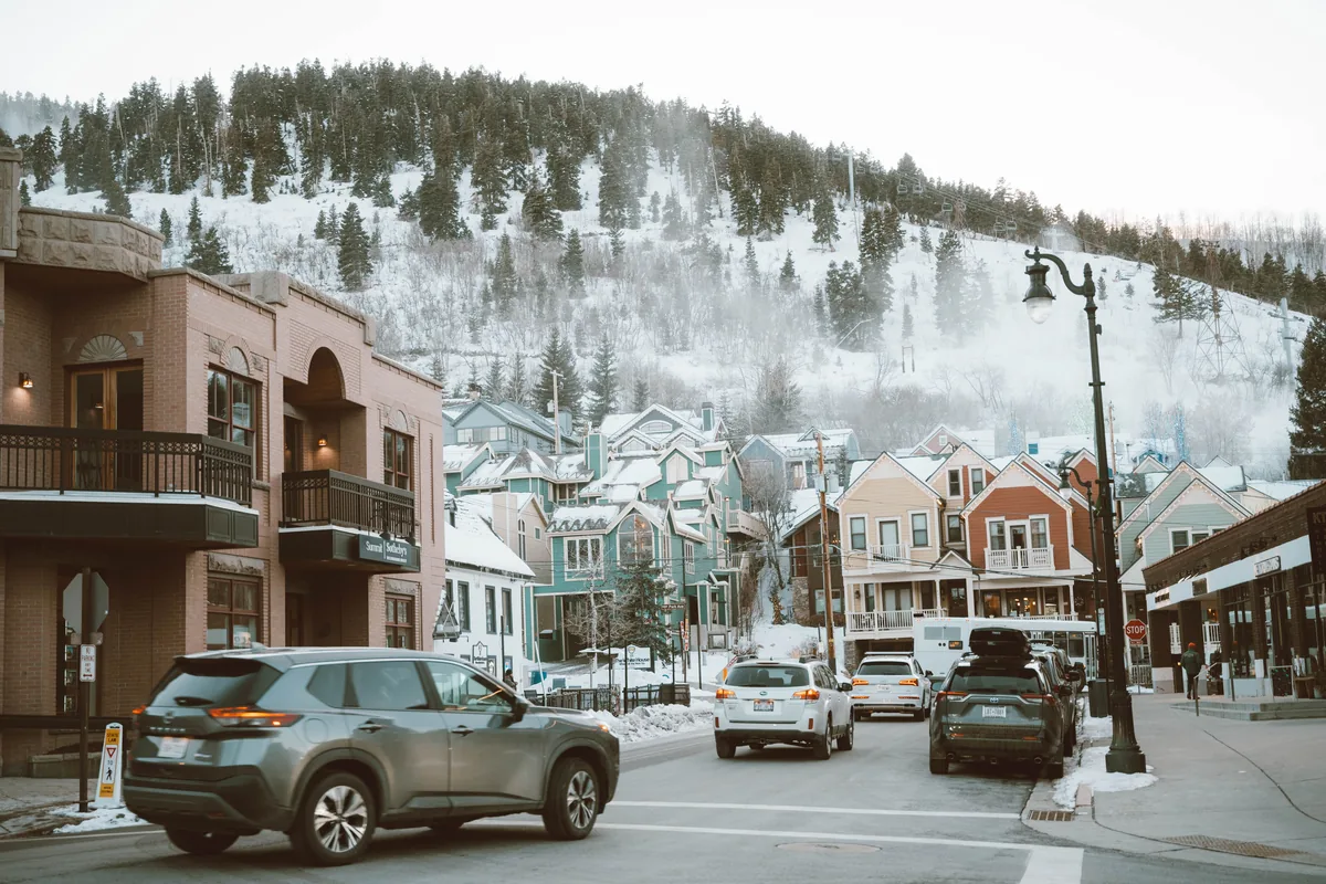 Utah's Best Vacation Rentals management fees, Snowy Park City street lined with colourful shopfronts below a ski hill