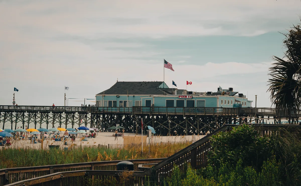 Coastline Resorts alternatives for Airbnb owners, Pier building flying flags above the sand and beach umbrellas