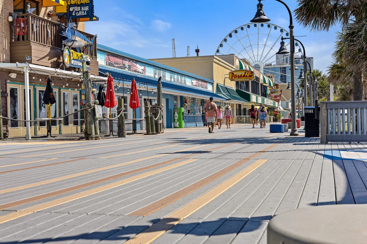 Coastline Resorts management fees, Seafront boardwalk lined with shops beneath a Ferris wheel