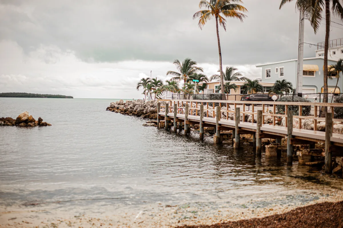FunStay Florida alternatives for Airbnb owners, Timber pier running out from a rocky Florida shoreline under grey cloud