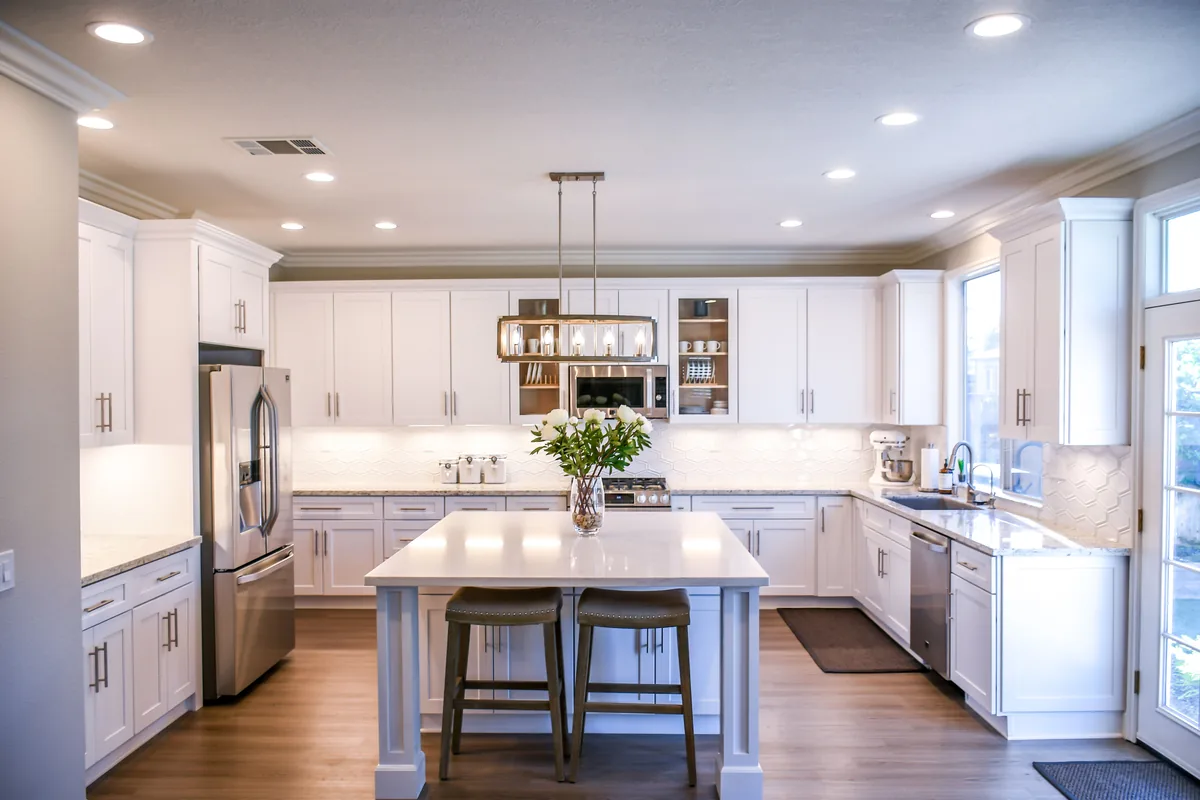 Casago management fees, White kitchen with a central island under pendant lights