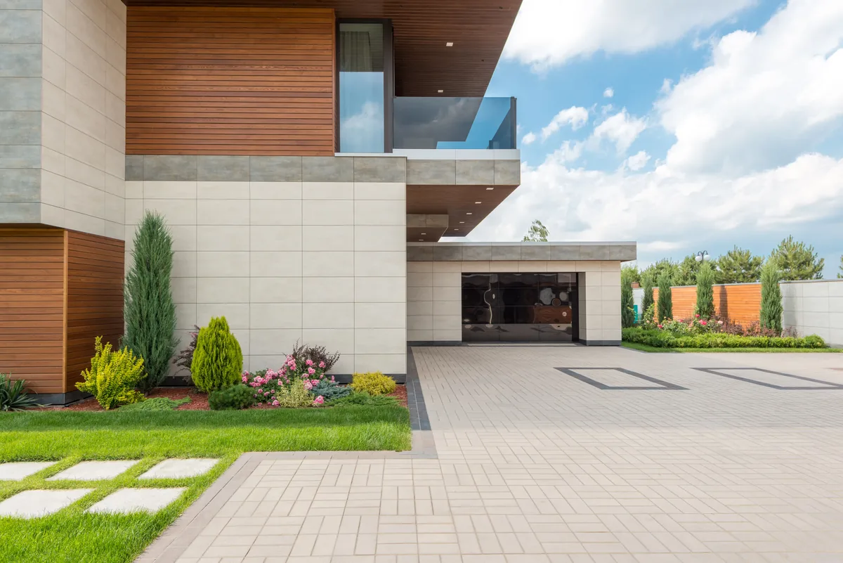 Evolve alternatives for vacation rental owners, Modern stone and timber house behind a paved path and clipped shrubs