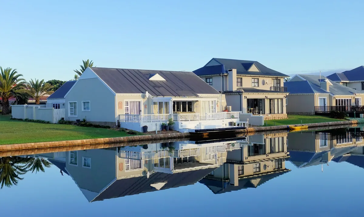 iTrip alternatives for Airbnb owners, White canal-side houses reflected in still water