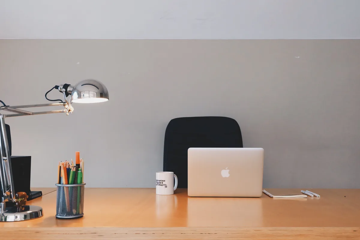 RedAwning management fees, Laptop, lamp and pen pot on a bare wooden desk