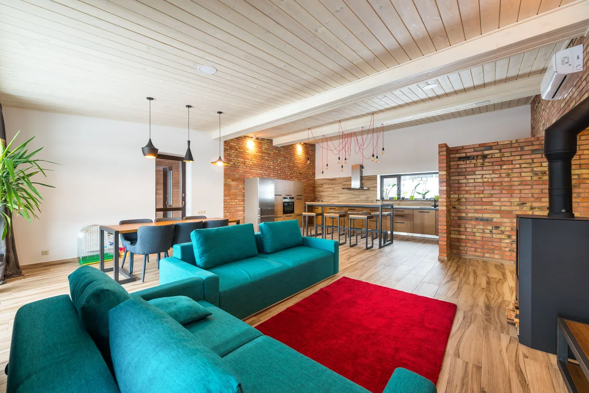 Vacasa management fees, Open-plan living room with teal sofas and a red rug