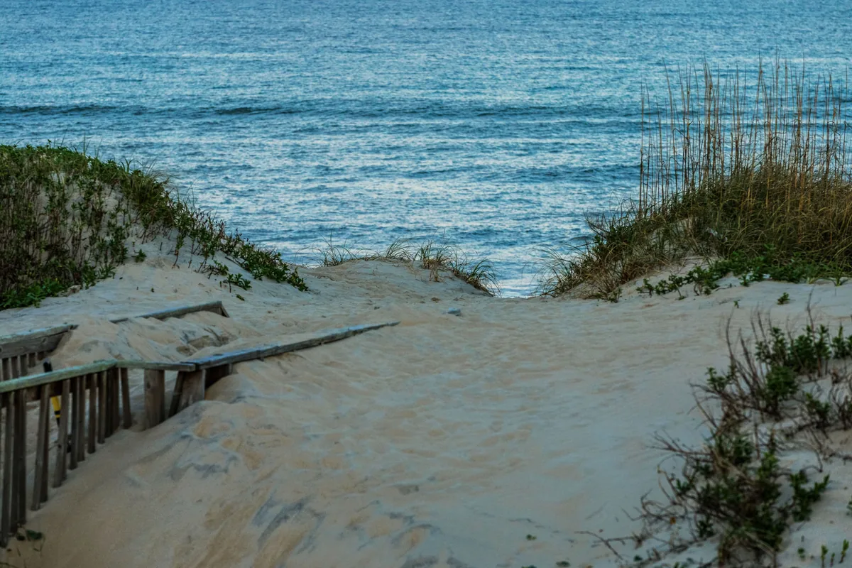 Twiddy & Company management fees, Sand path through dunes opening onto turquoise water