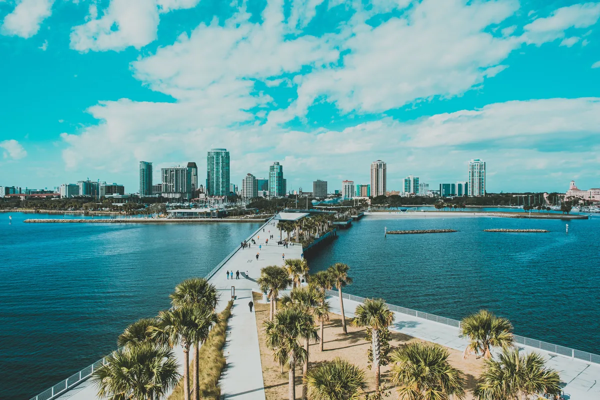 Emperor Rentals management fees, Palm-lined approach to a Florida pier with the skyline behind
