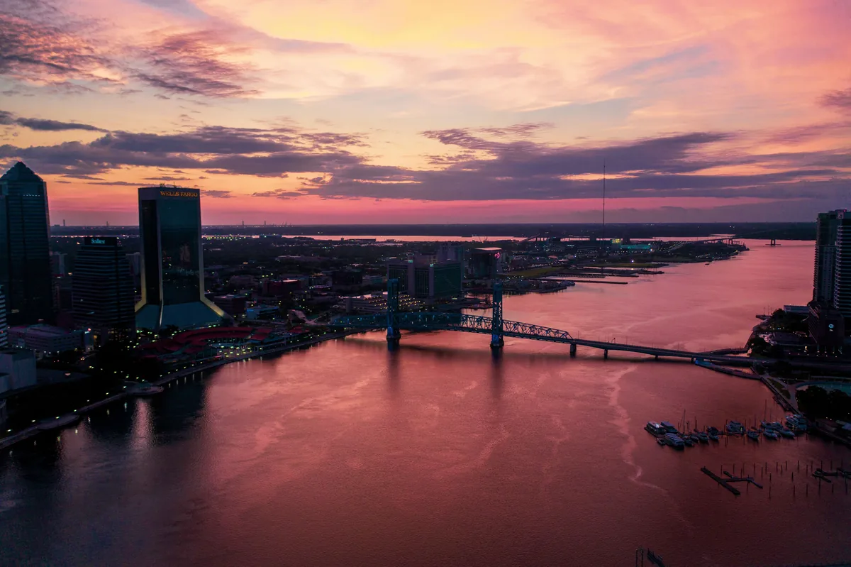 JaxBNB management fees, Pink sunset over the river winding through downtown Jacksonville