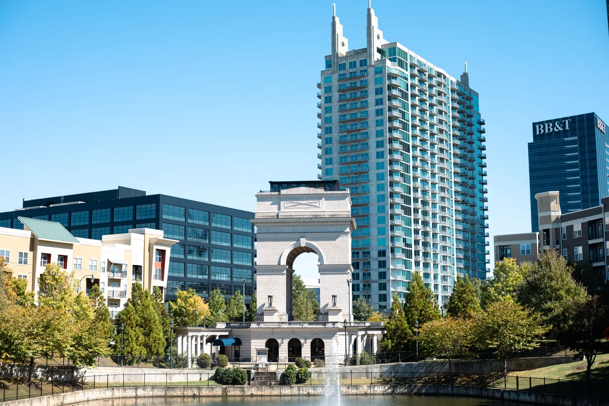 Hitlist Rental Management management fees, Stone arch and glass apartment towers beside a city pond