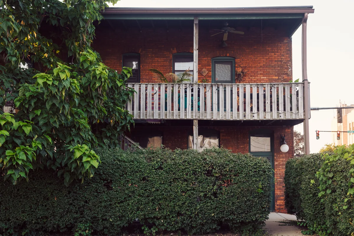 ChicagoHostCo management fees, Two-storey brick house with a timber porch behind a clipped hedge