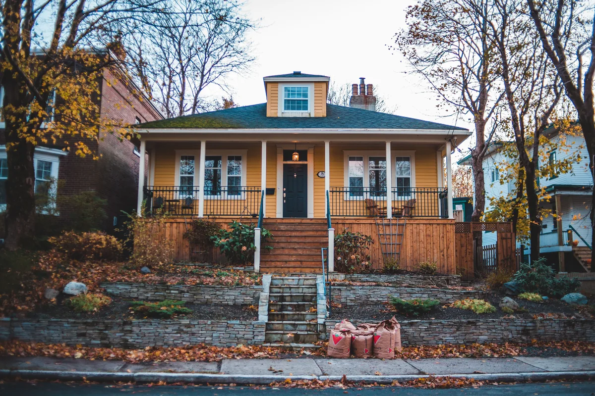 BearBnB alternatives for Airbnb owners, Yellow bungalow with a covered porch among fallen autumn leaves