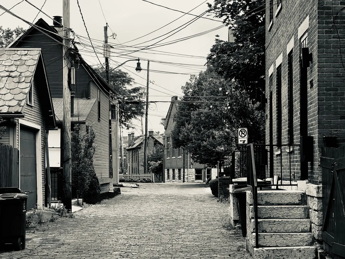 Jungle House alternatives for Airbnb owners, Narrow alley between timber and brick houses in black and white