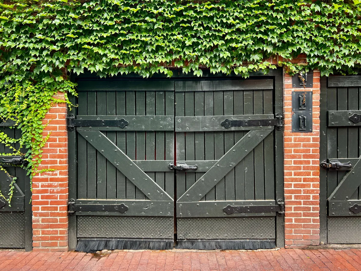 GH Hospitality alternatives for Airbnb owners, Green timber gates set in a brick wall under a mass of ivy