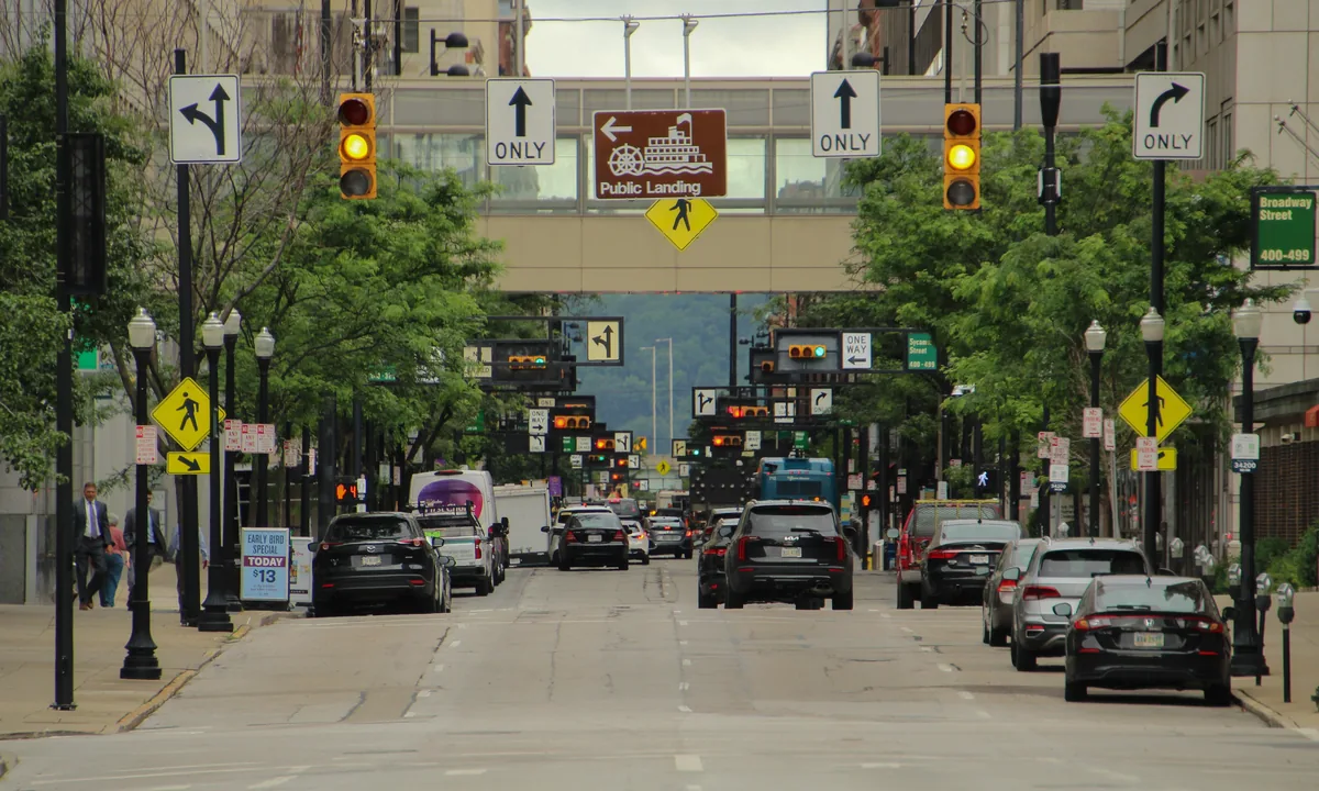Liberty Hill Rentals management fees, City street with traffic signals and parked cars between low buildings