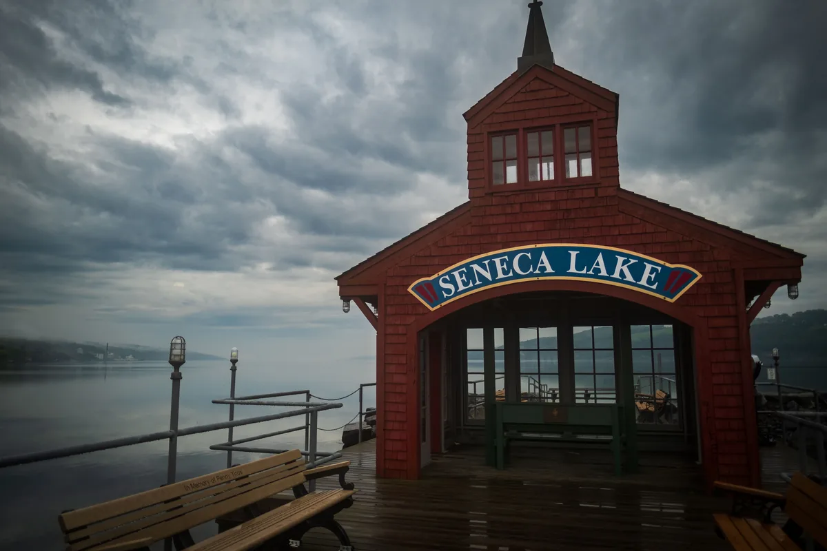 FLX Rentals management fees, Red timber boathouse marked Seneca Lake beside a dock