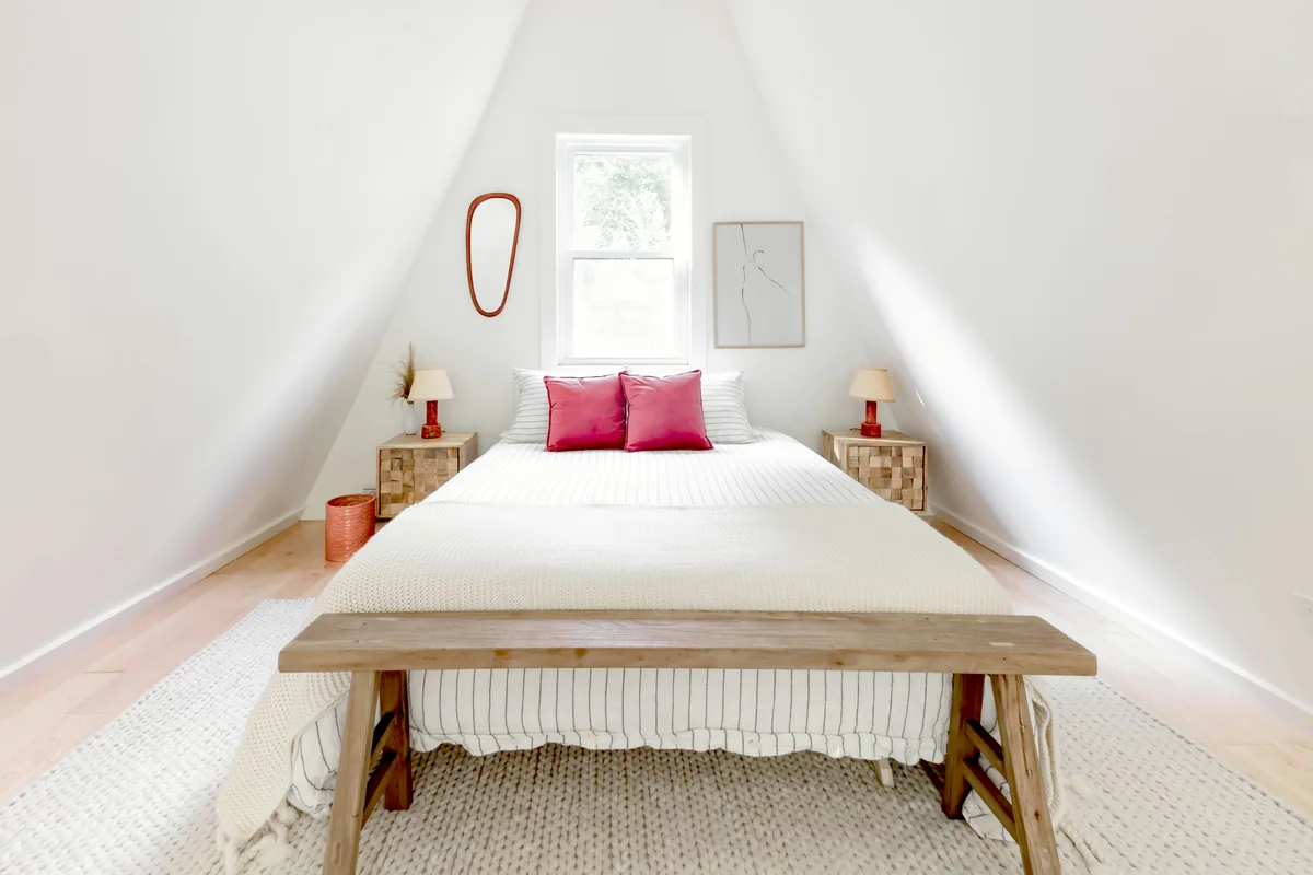 Alluvion Vacations alternatives for Airbnb owners, Bed made up under a sloping attic ceiling with pink cushions