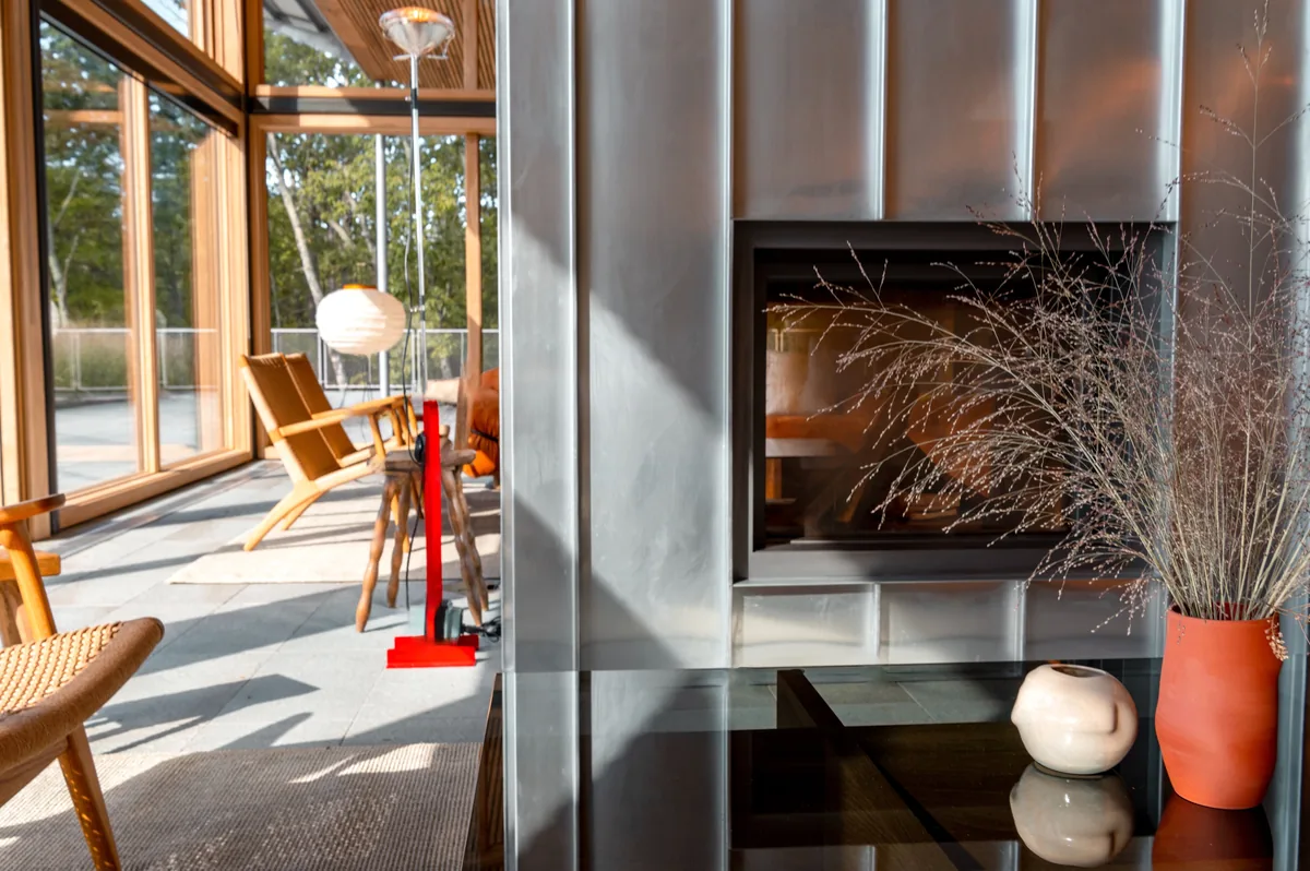 Alluvion Vacations management fees, Living room with a fireplace and tall windows onto the trees