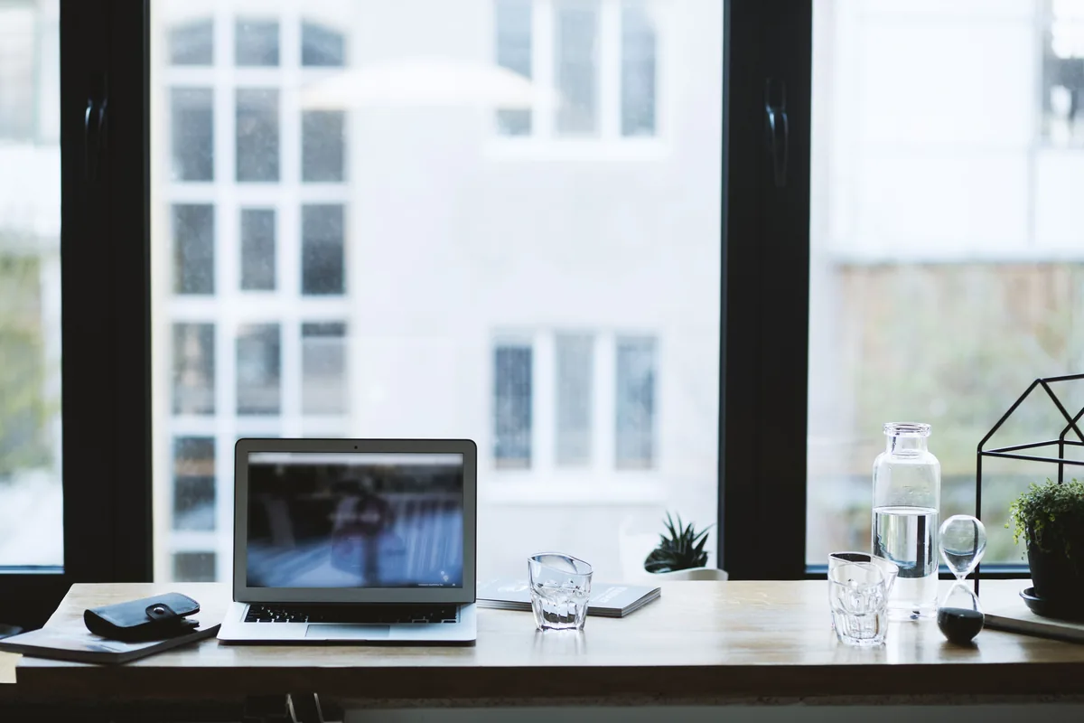 Checkmate Rentals management fees, Laptop open on a desk in front of a window looking onto a building
