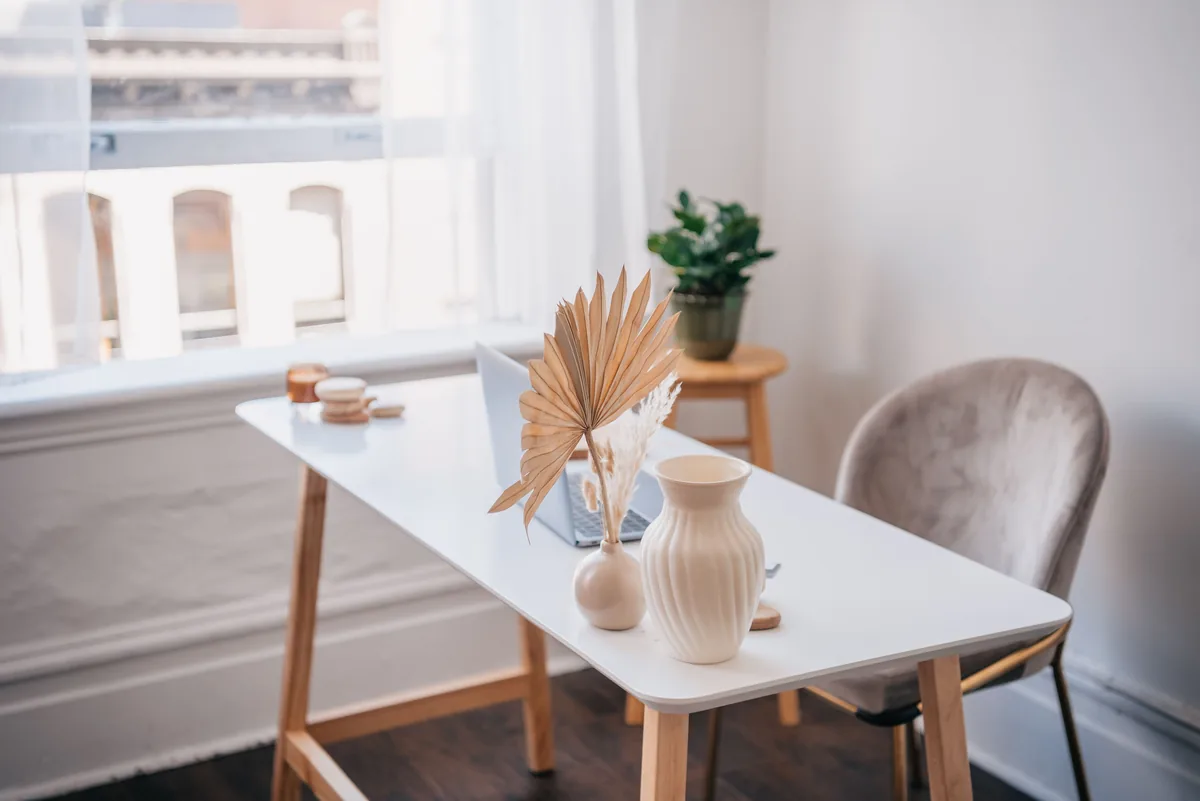 STR Assistance management fees, White table with a chair, vases and a small plant by a window