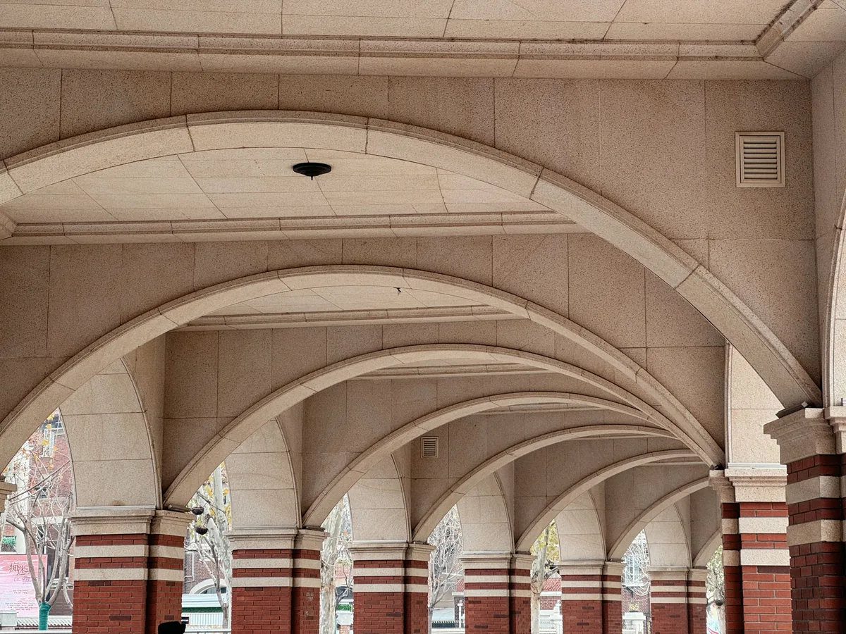 Jungle House management fees, Row of stone arches receding along a covered walkway