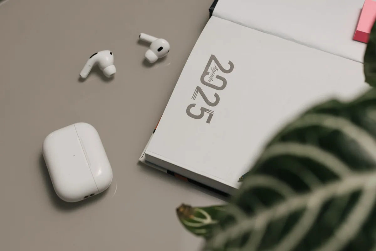 STR Assistance alternatives for Airbnb owners, Notebook, wireless earbuds and a leaf on a plain desk