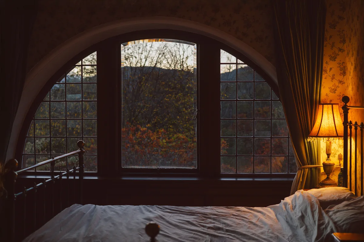 Bedroom with an arched window, warm lamp — Vrbo Host Fees: Comprehensive Guide to Maximize Your Rental Income