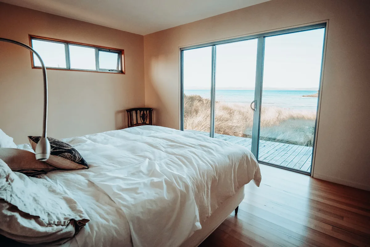 Bedroom with sliding doors to a beach — Airbnb Cleaning Jobs: How to Find Work and What Cleaners Earn