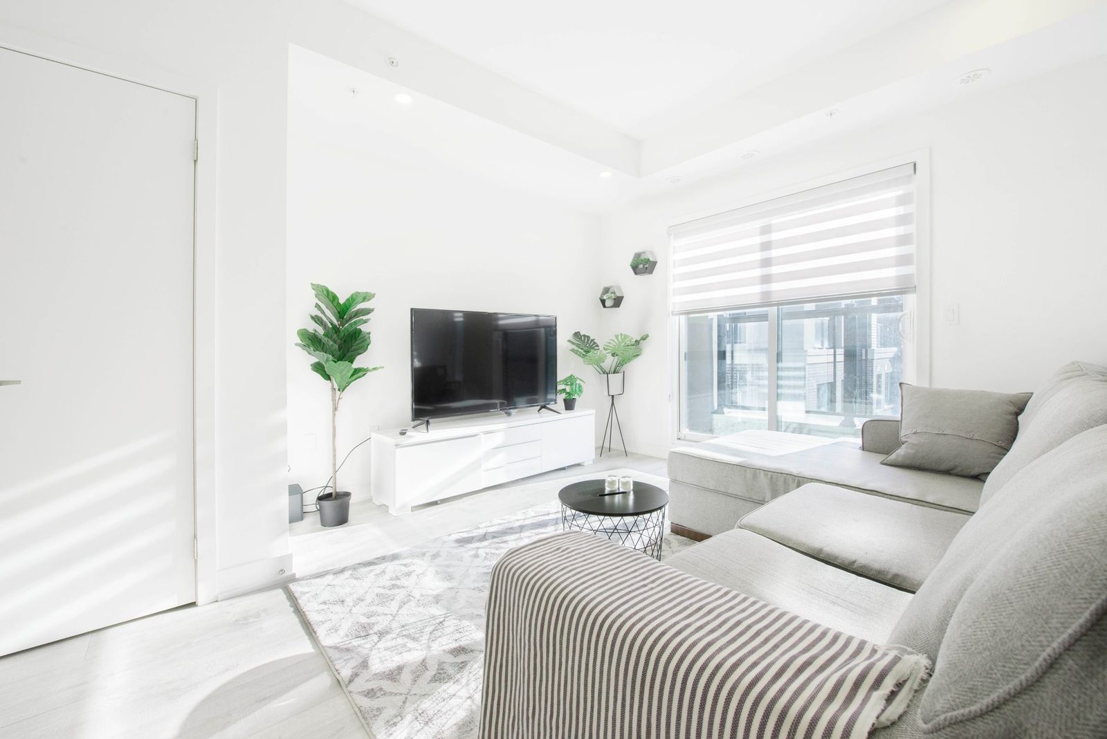 A bright condominium living room with a wall-mounted television