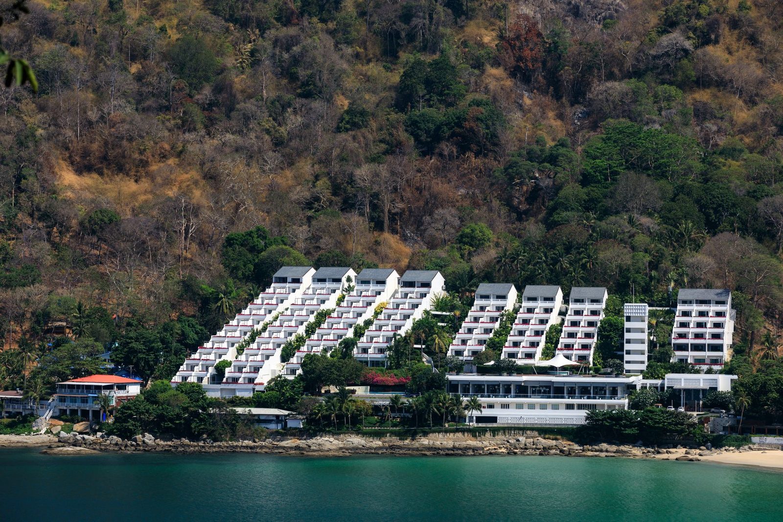 Villa and condominium terraces stepping down a green hillside above the sea