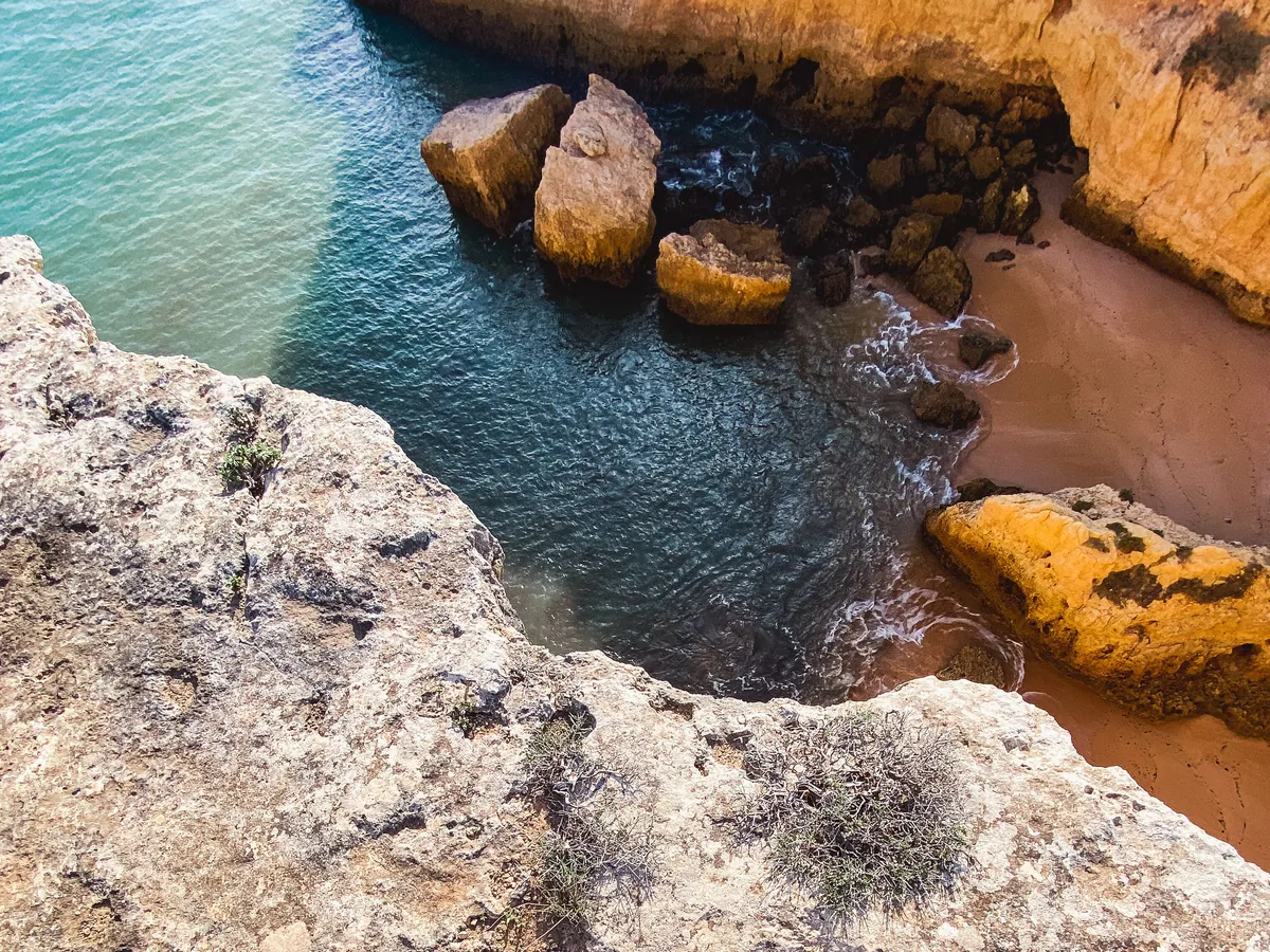 GuestReady alternatives for Portuguese owners, Aerial view of golden cliffs around an Algarve cove