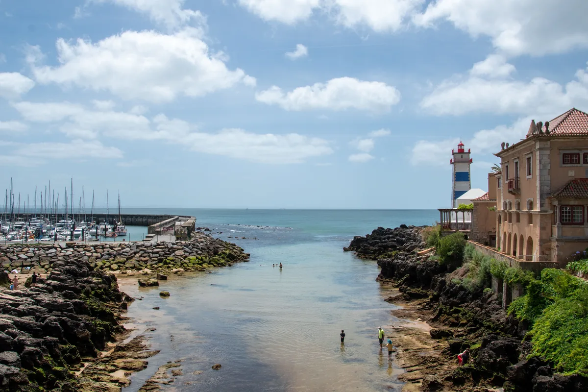 Feels Like Home management fees, Cascais marina and lighthouse beside the rocky shore