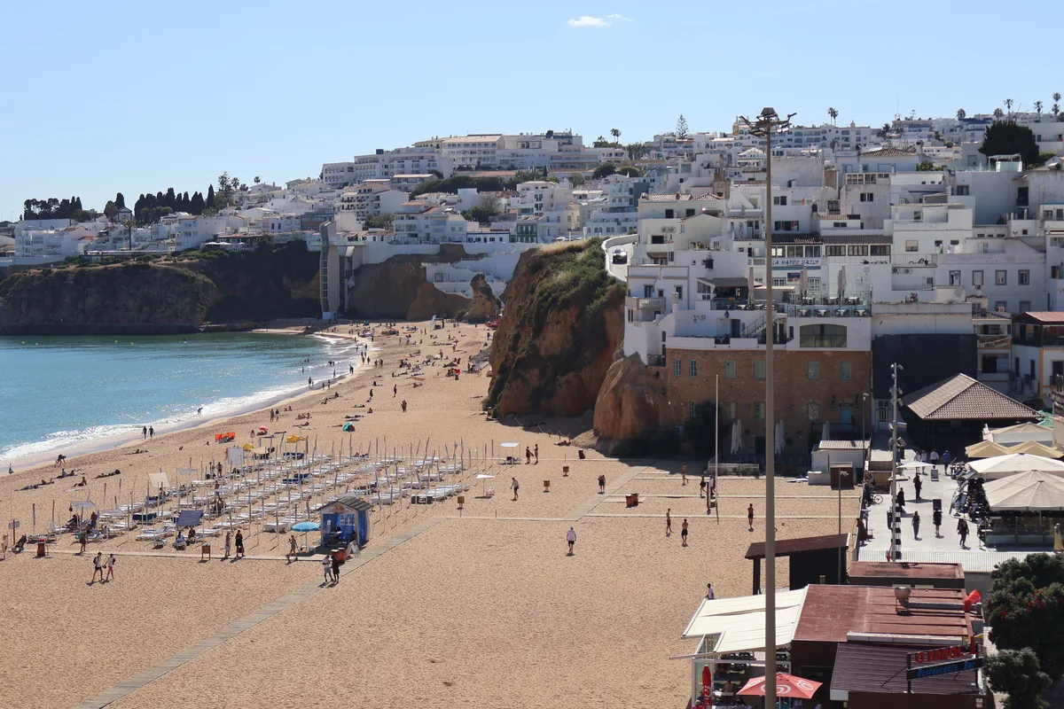 The Albufeira Concierge management fees, White Algarve buildings above a beach of sun loungers