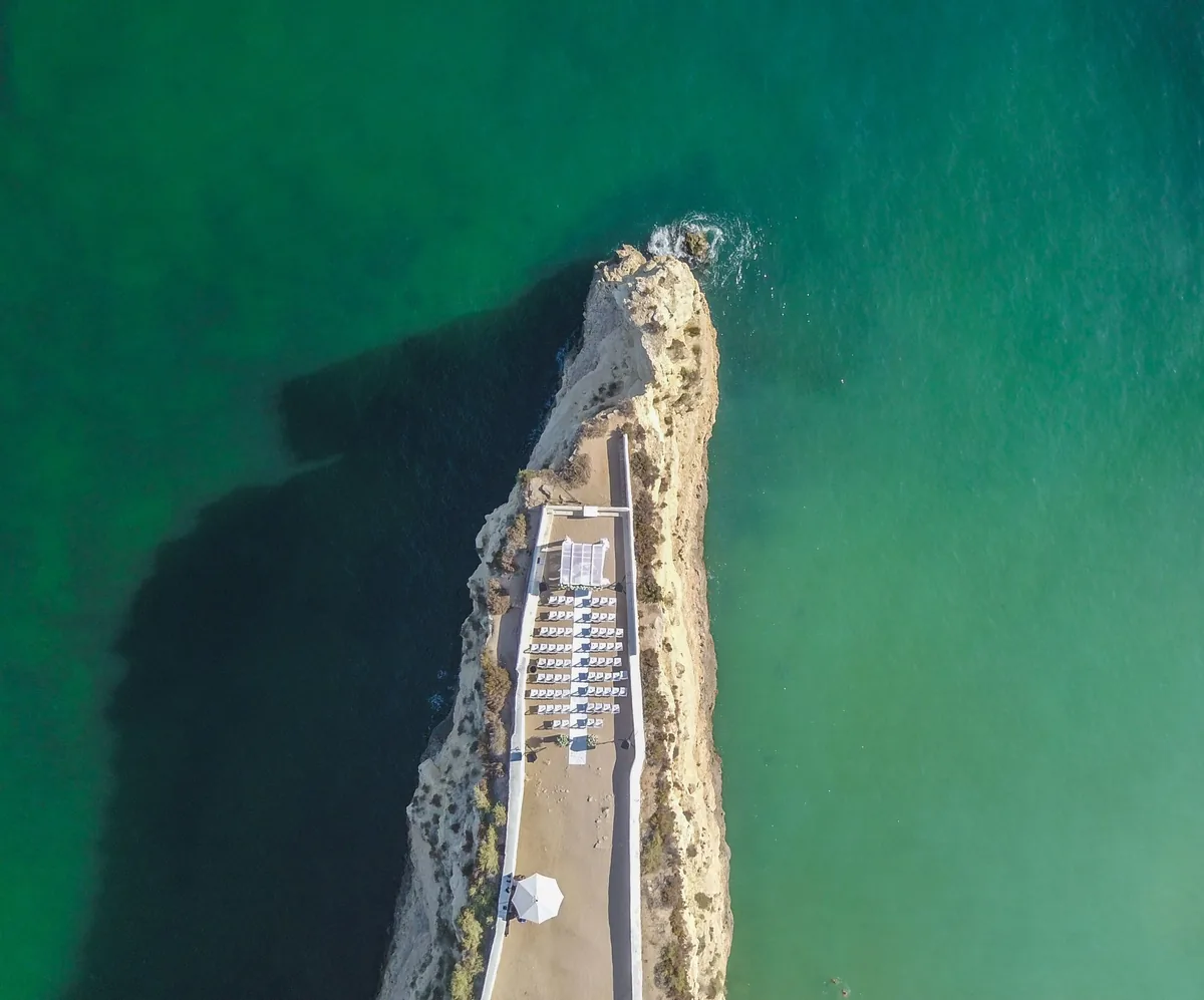Portugal vacation rental management fees, Aerial view of a headland and turquoise water on the Algarve coast