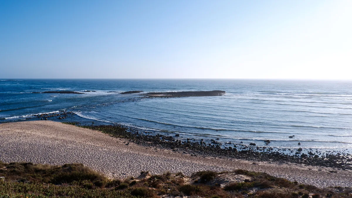 Airnest REIM management fees, Pebbled foreground above a bay on the Alentejo coast