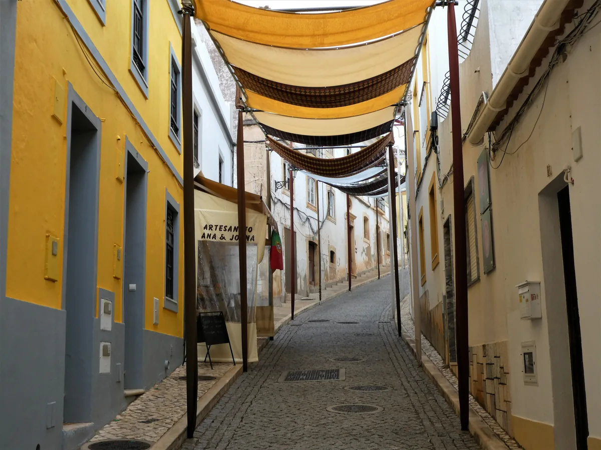Vista Algarve alternatives Portugal, Narrow awninged street of yellow and white walls in Silves