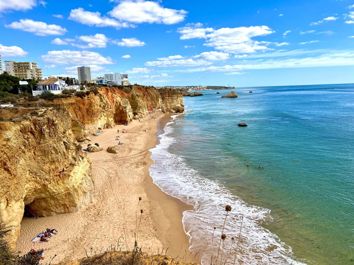 An Algarve beach below cliffs, with apartment blocks along the clifftop