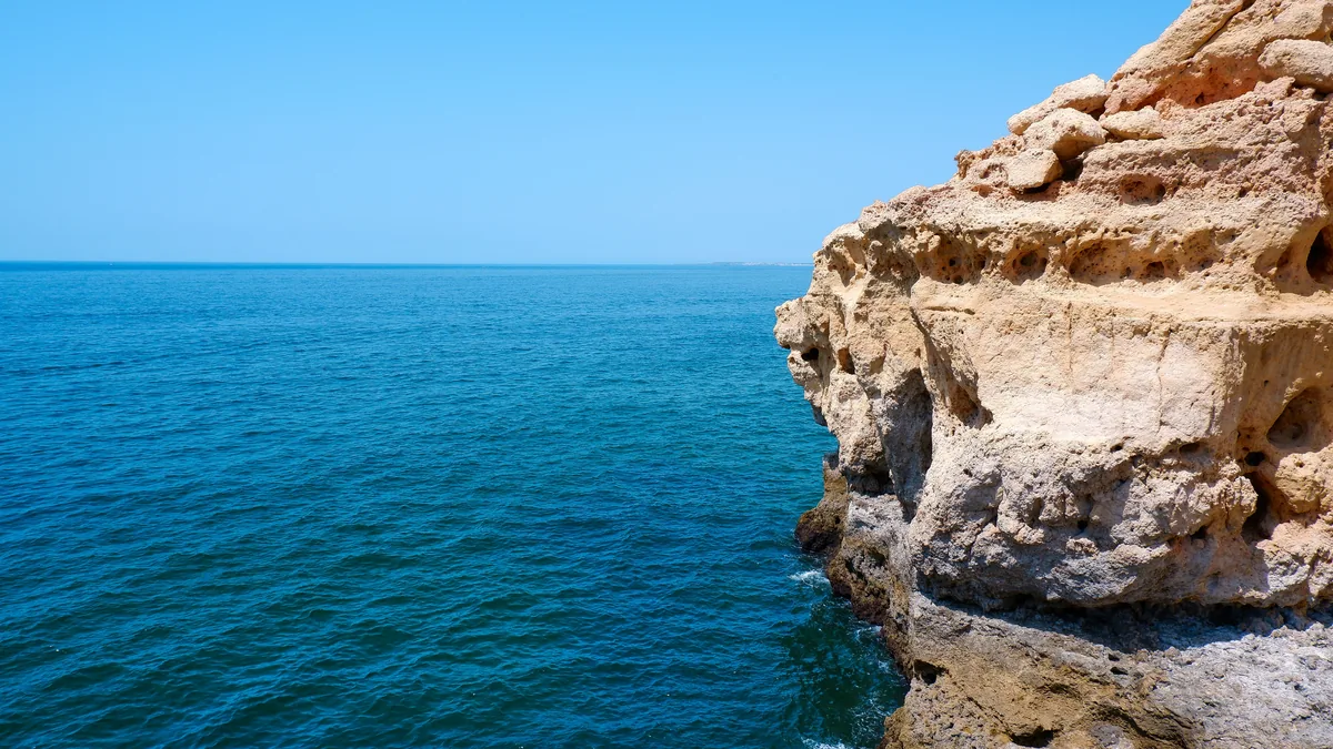 Weathered limestone rock meeting clear water on the Algarve coast