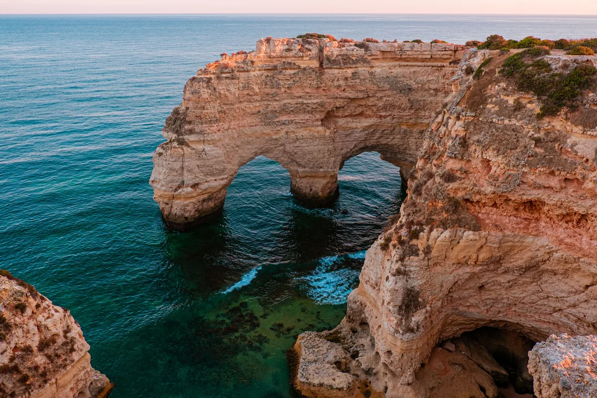 A limestone sea arch on the Algarve coast at low sun