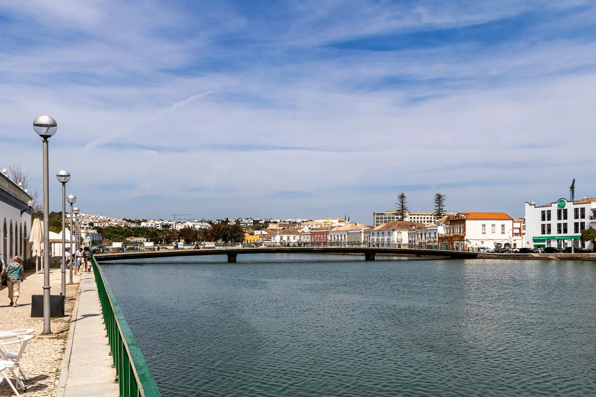 A riverside town with a bridge and low white and terracotta buildings