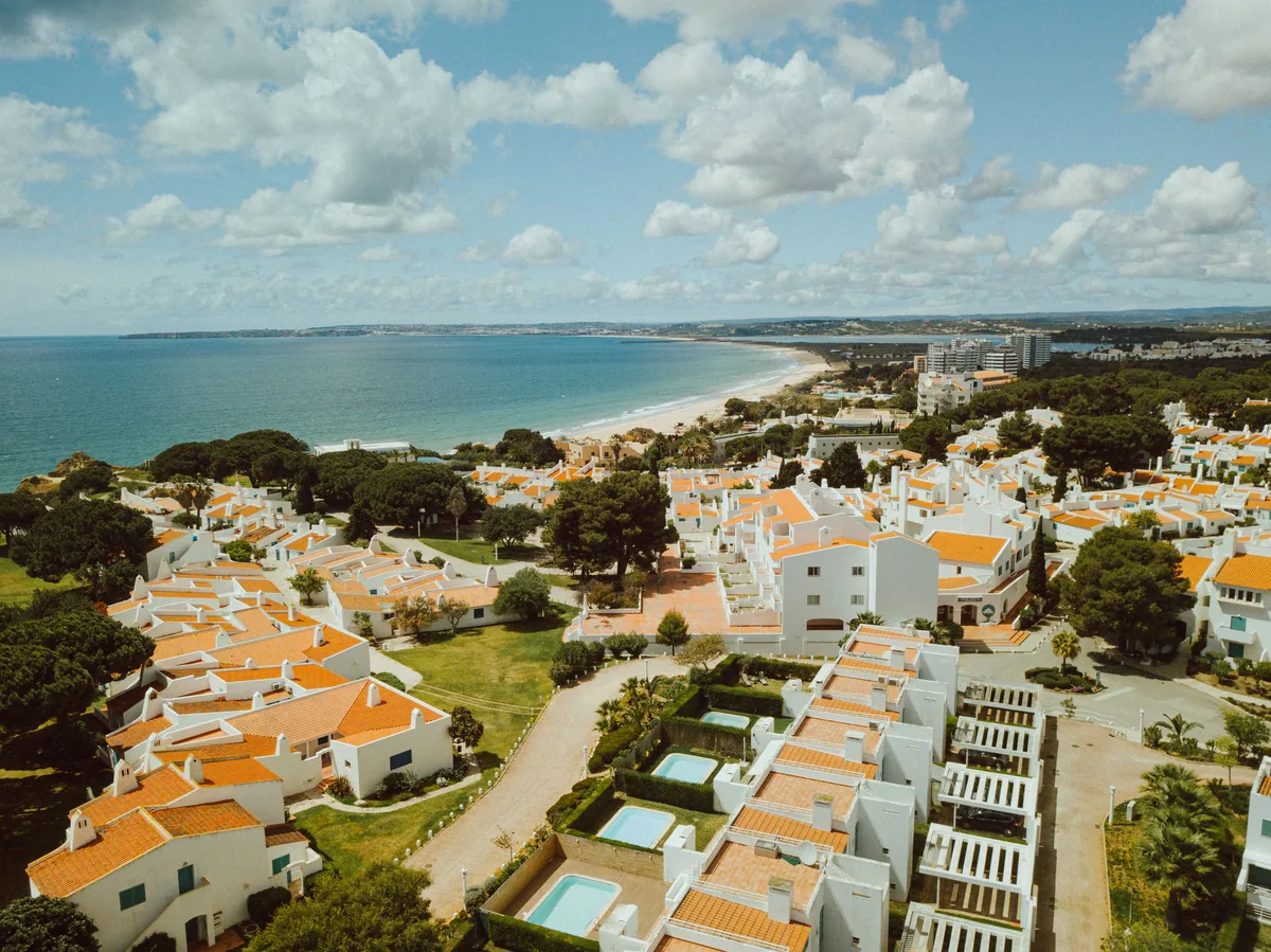 White villas with terracotta roofs stepping down towards an Algarve bay