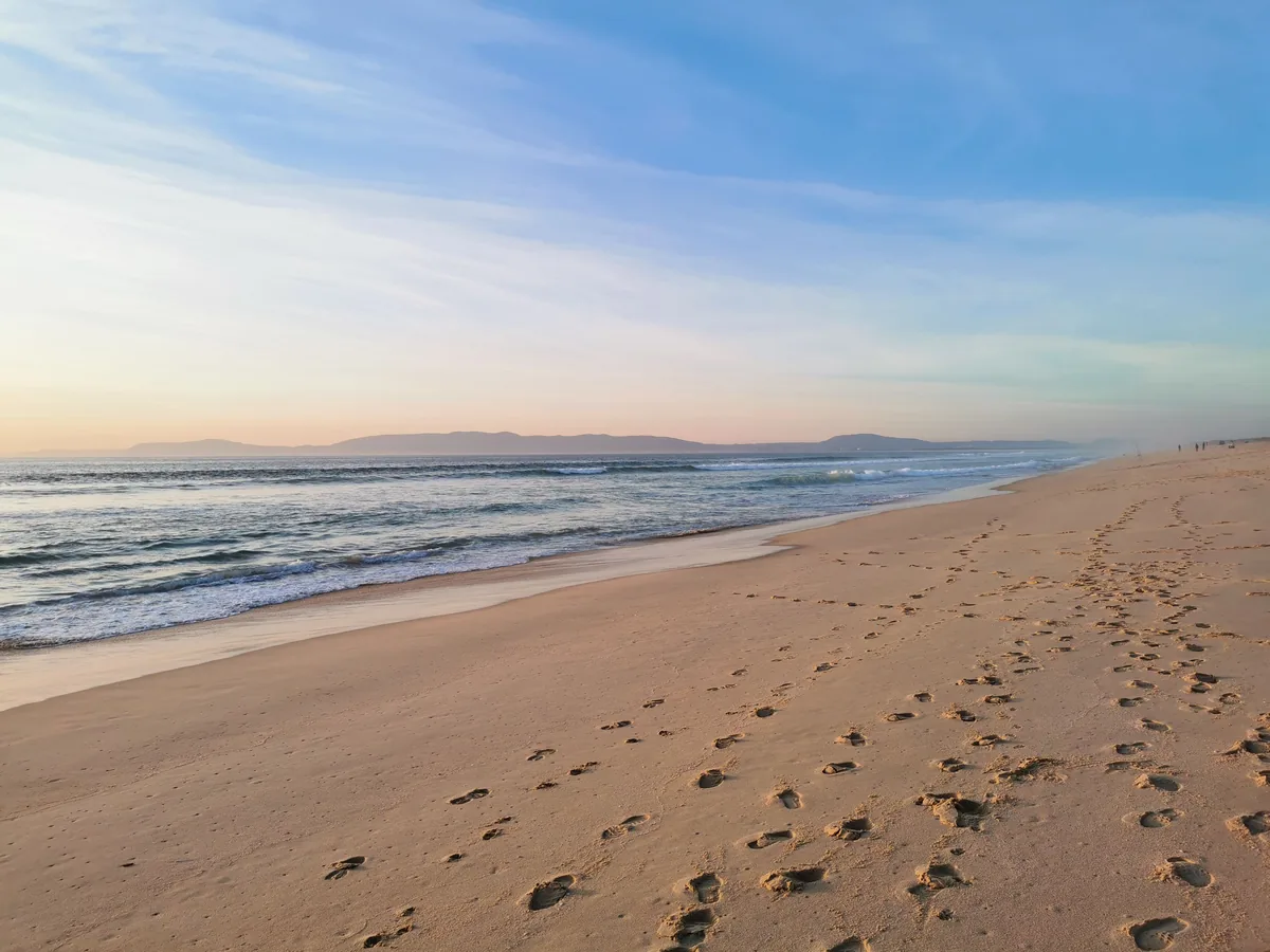 An empty sand beach and low surf on the Alentejo coast at sunset