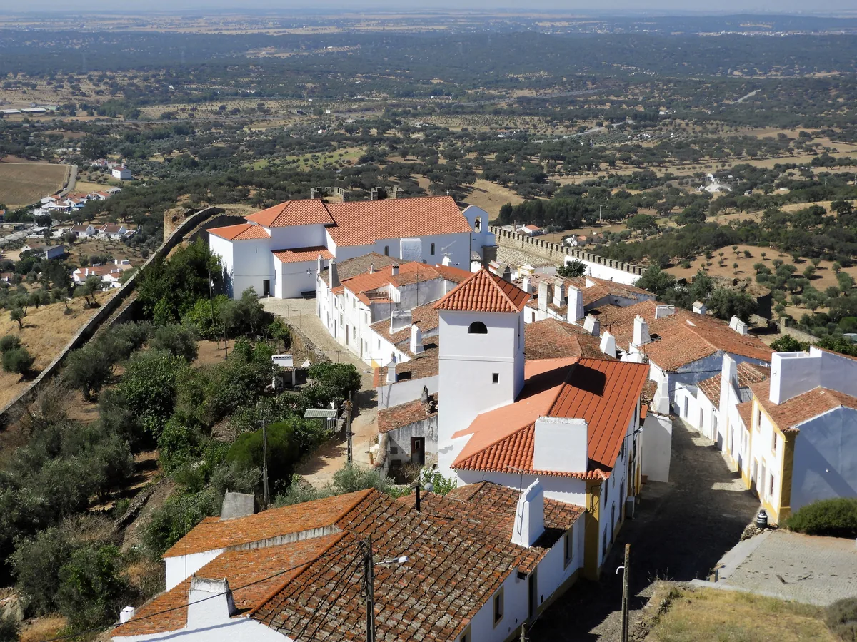 White houses and terracotta roofs of an Alentejo village above the plain