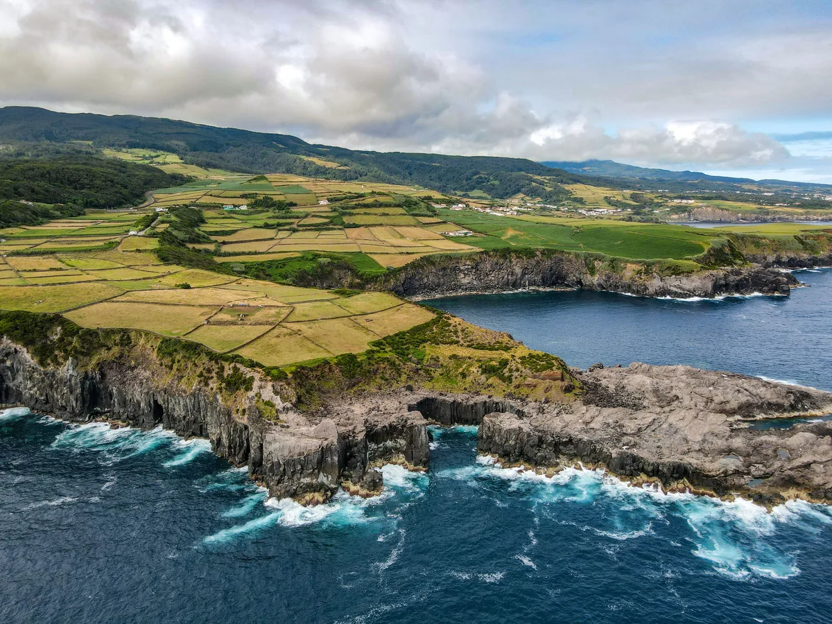 Farmland above black volcanic cliffs in the Azores