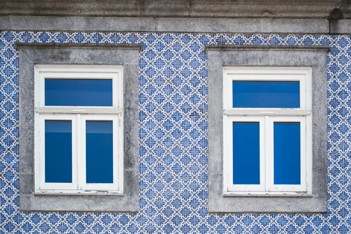 A blue azulejo-tiled facade with white window frames
