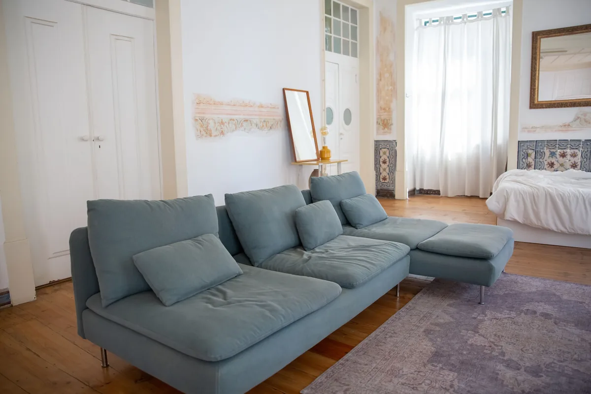 A living room furnished for short stays, with the bed beyond